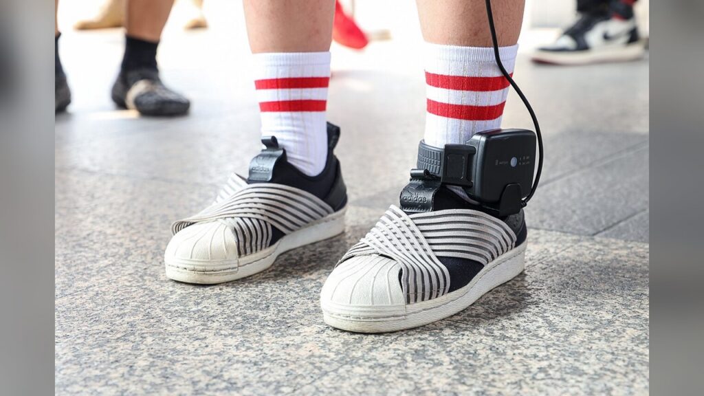 electronic ankle monitor, GPS tracking device strapped to leg by ICE to monitor movement.