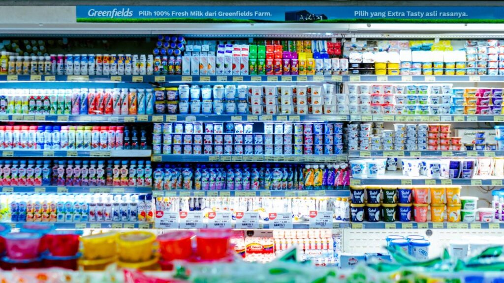 filmed destruction of dairy products in grocery aisles, Footage showing individuals filming the destruction of dairy products inside a grocery store aisle.